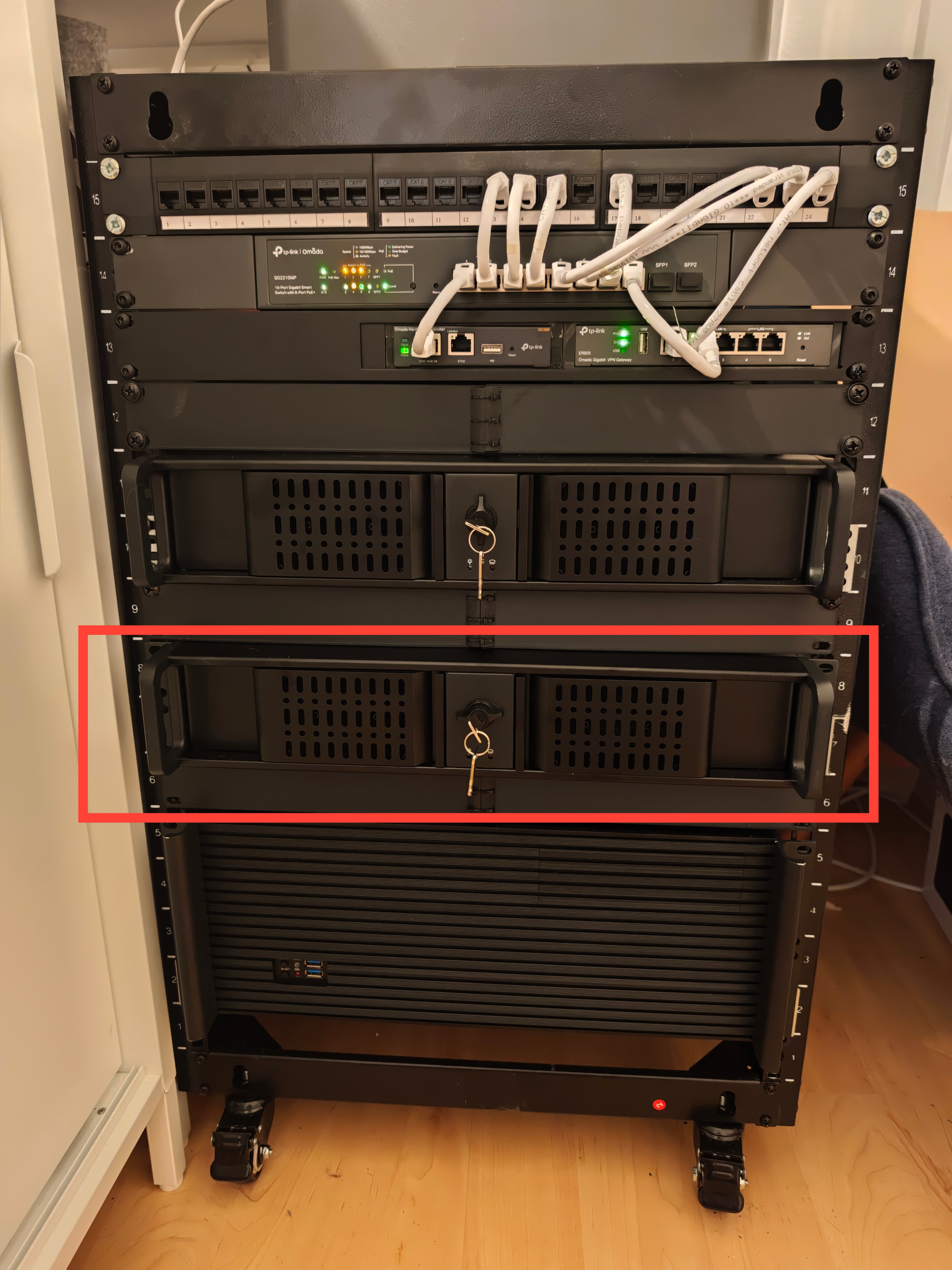 A 15 unit high 19 inch server rack showing a bigger server on the bottom, followed by two identical smaller servers on top. Networking equipment is connected by white patch cables on top.
